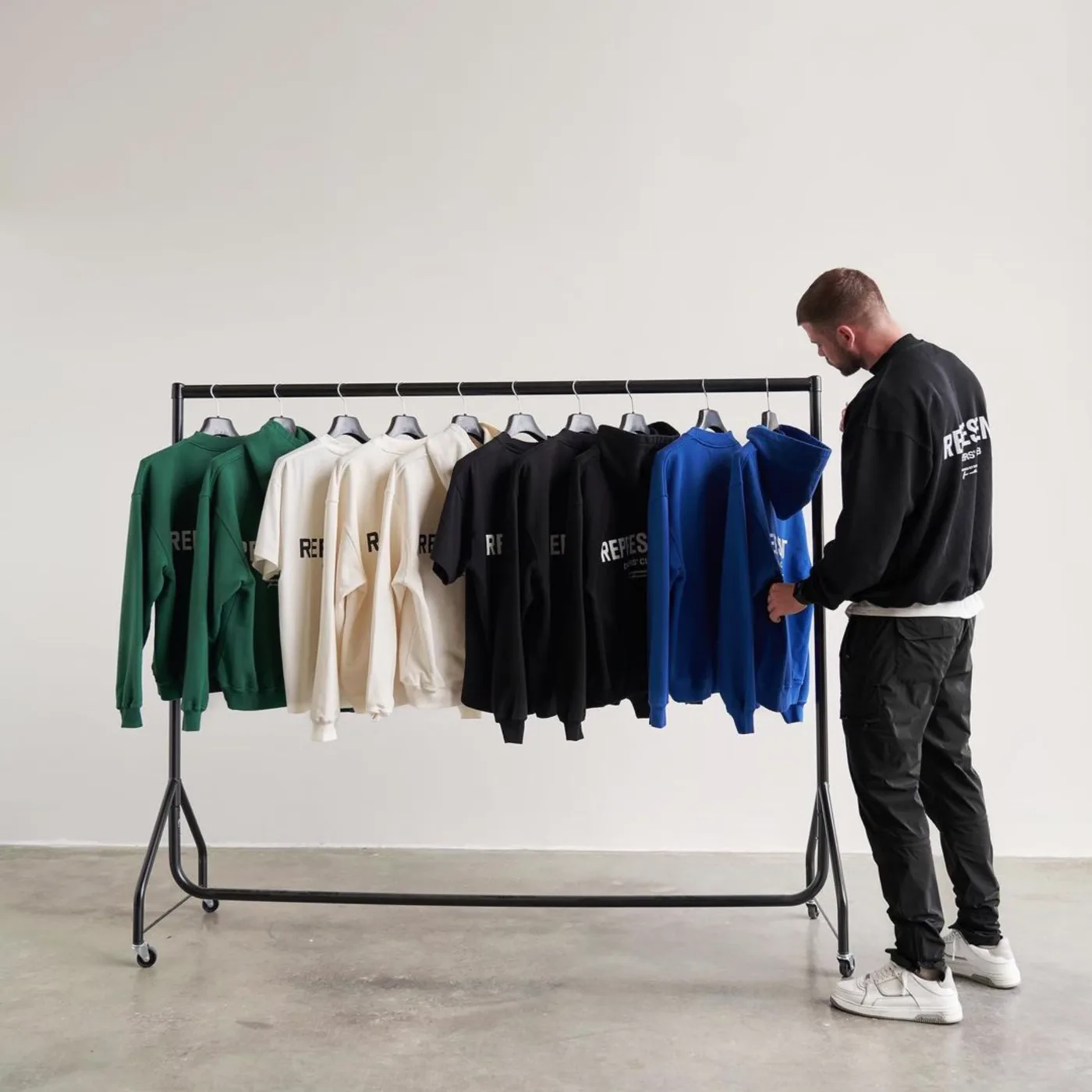 Colour-sorted hoodies and sweatshirts displayed on a garment rail