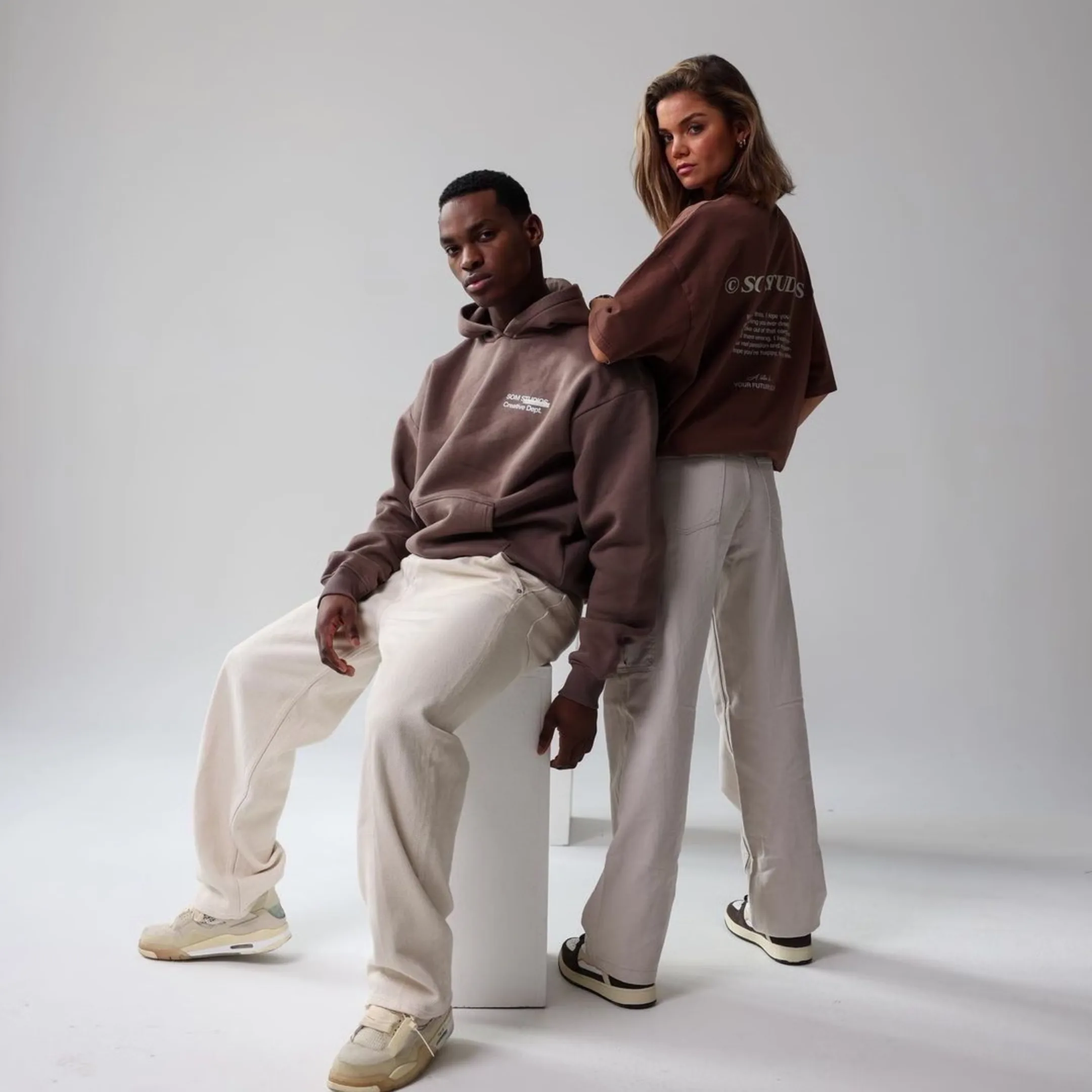 Two models presenting a coordinated brown and neutral apparel collection
